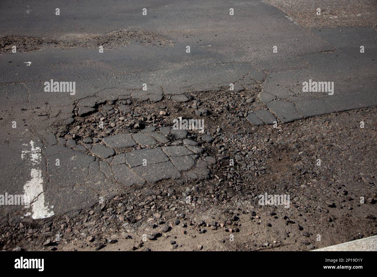 Damaged asphalt road with potholes caused by freezing and thawing ...