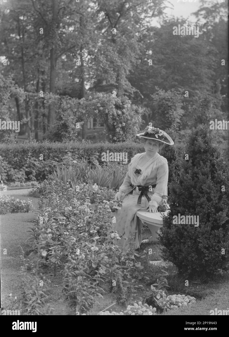 Truesdale, W., Mrs., standing in a garden, 1915 July 6. Stock Photo