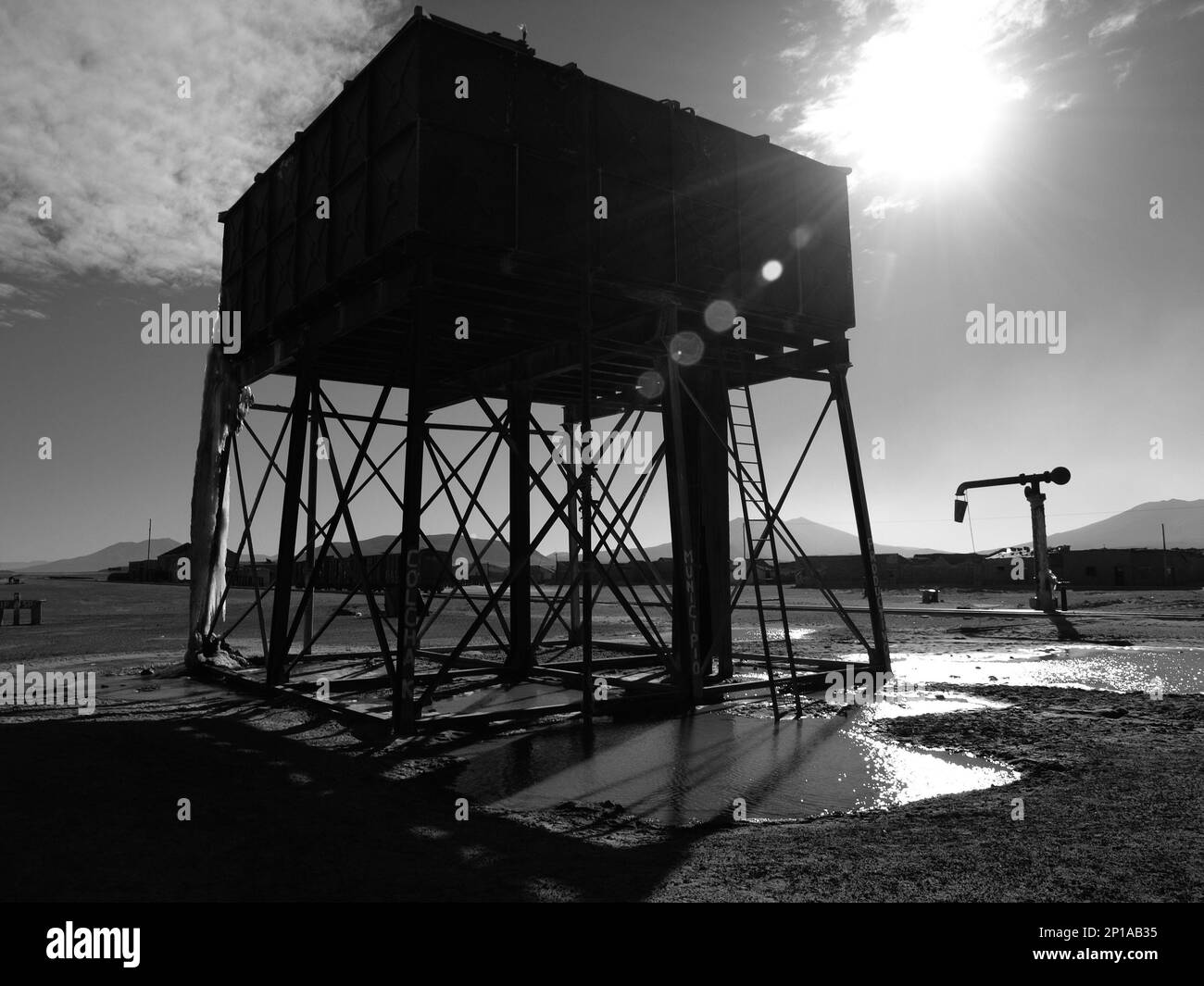 Vintage railroad water tank and pump in sunny day, Bolivia. Black and white image Stock Photo