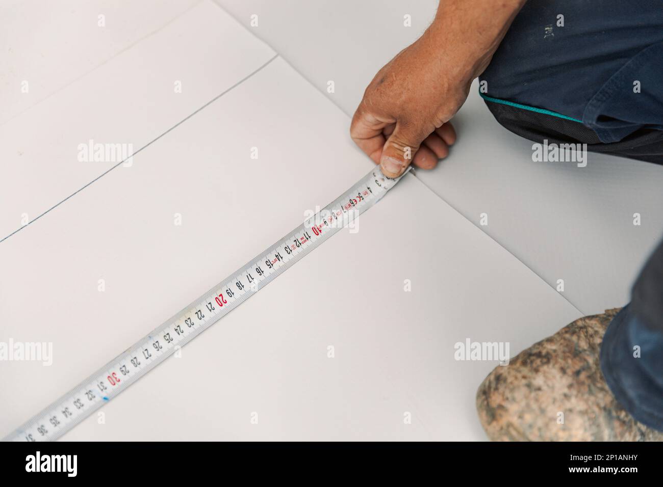 Worker measures with roulette pvc membrane to be cut Stock Photo