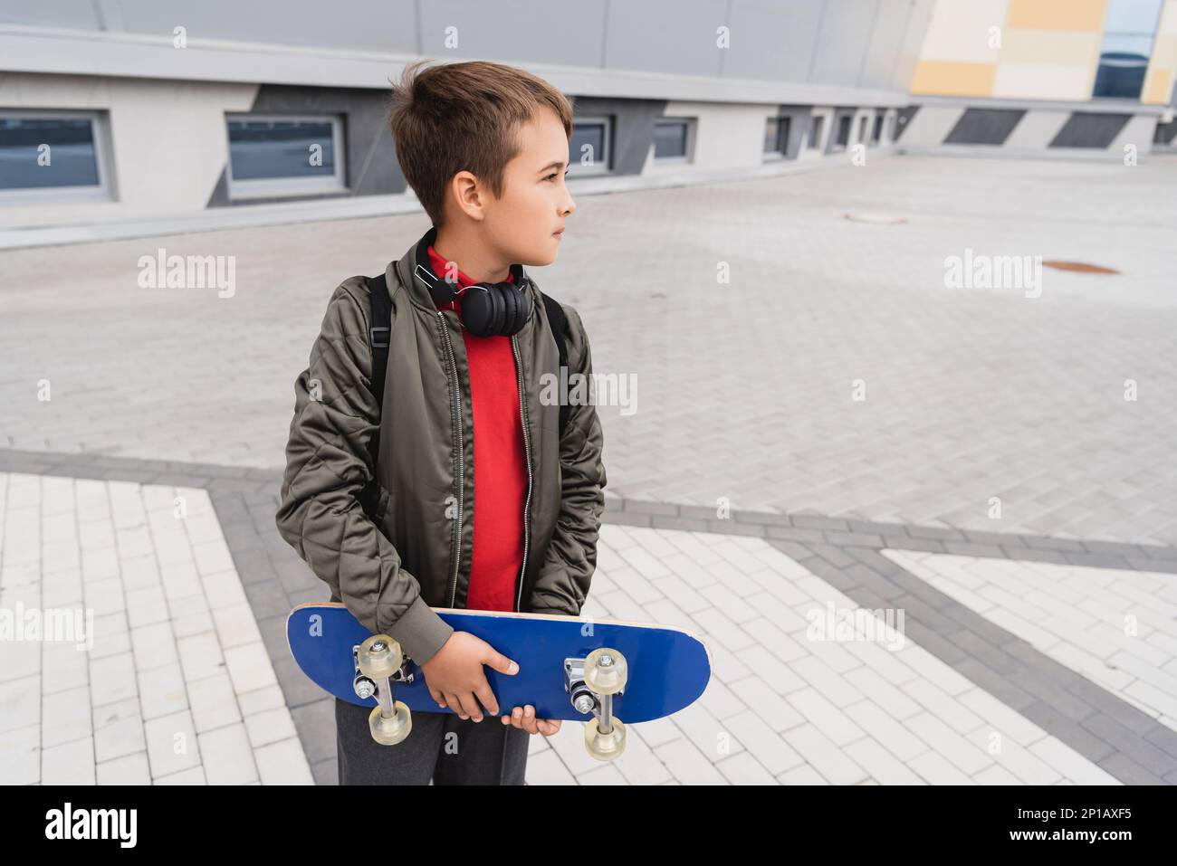 preteen boy in bomber jacket and wireless headphones holding penny