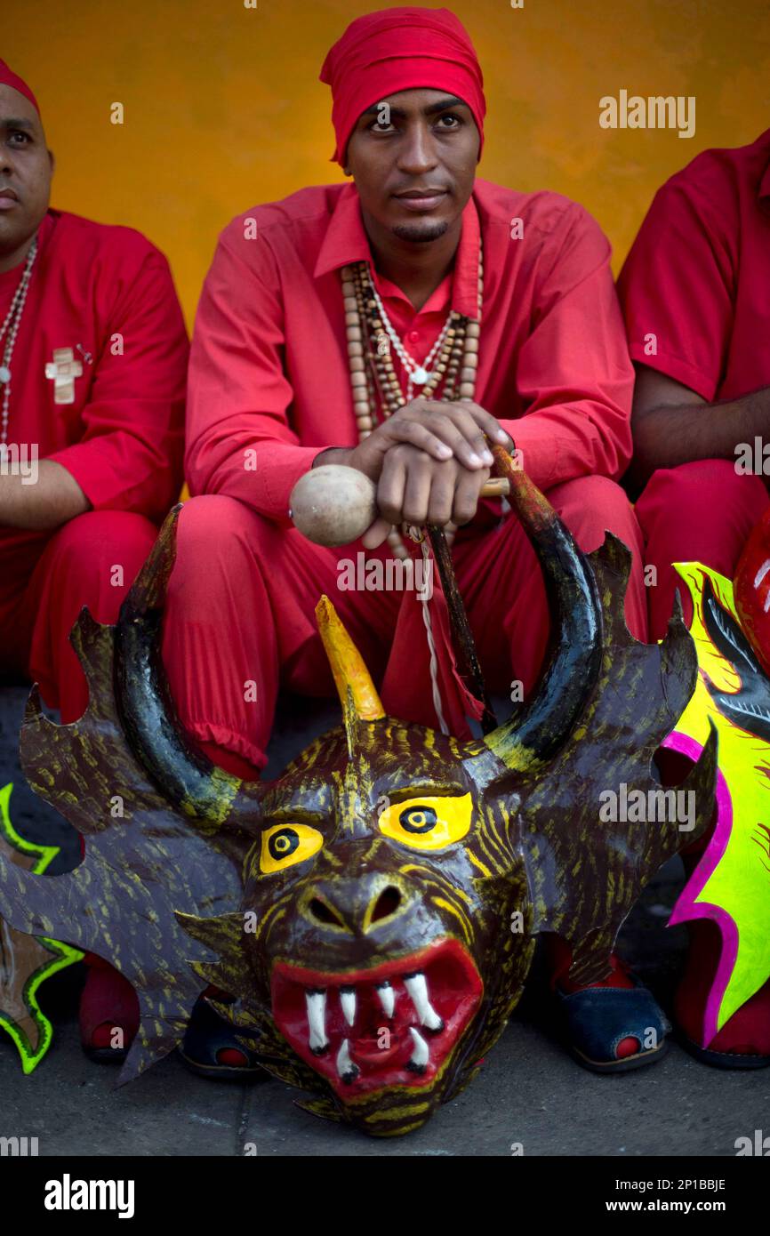 A man dressed as a dancing devil sits on the sidewalk before the start of  Corpus Christi celebrations in San Francisco de Yare, Venezuela, Thursday,  May 26, 2016. The Devil Dancing of