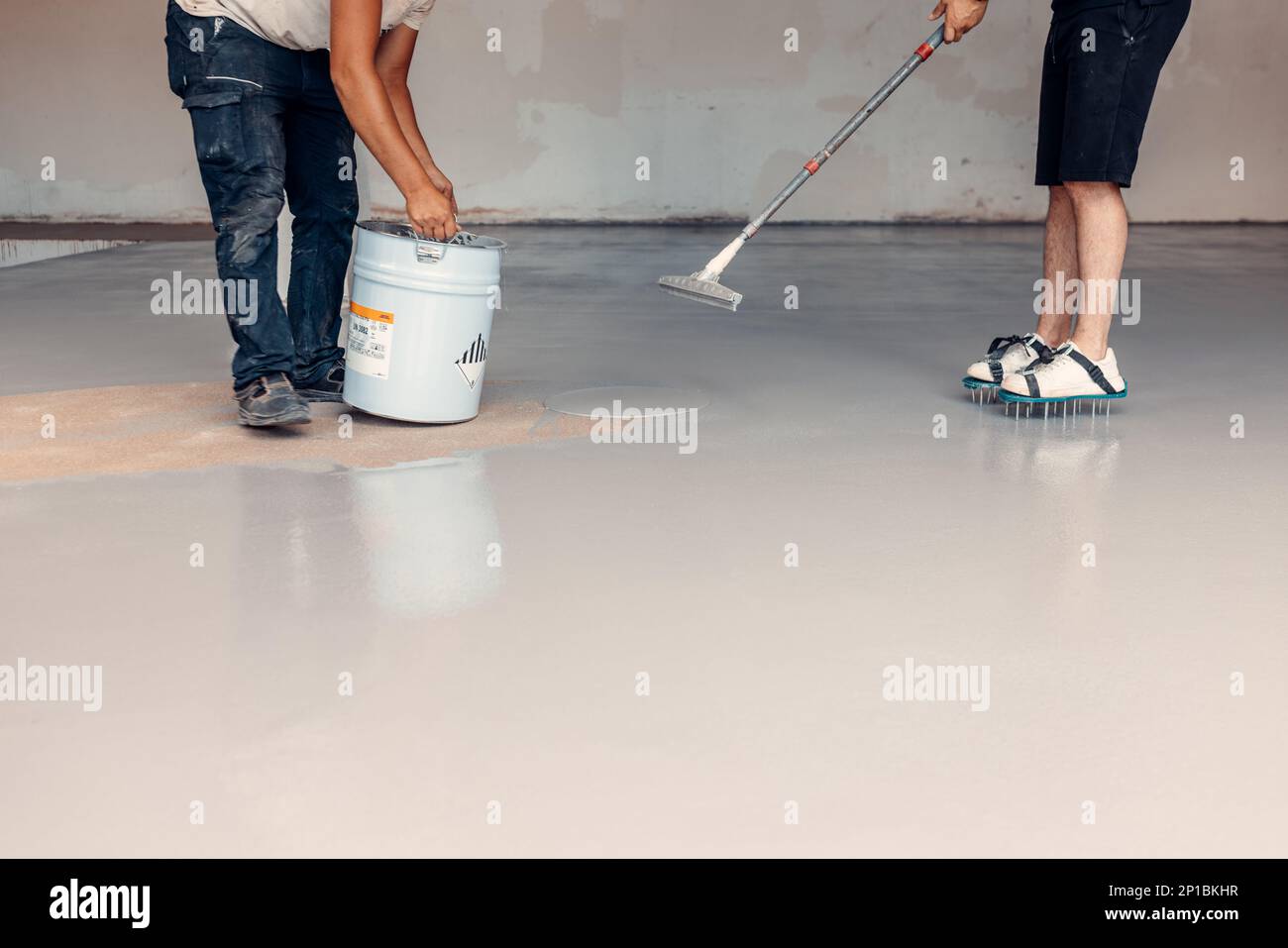 A construction worker apply grey epoxy resin in an industrial hall ...