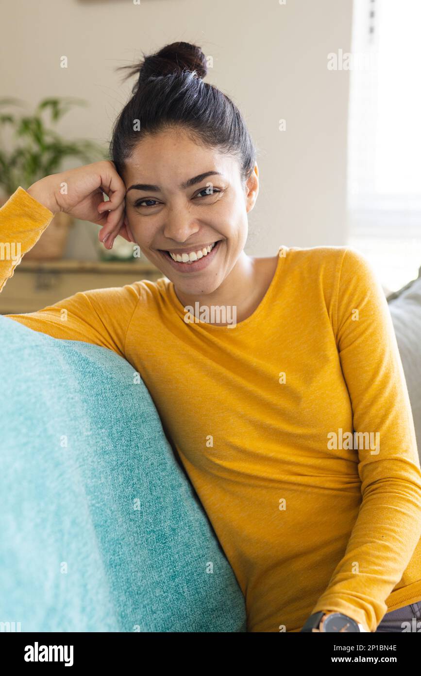 Portrait of happy biracial woman sitting on sofa and smiling Stock ...