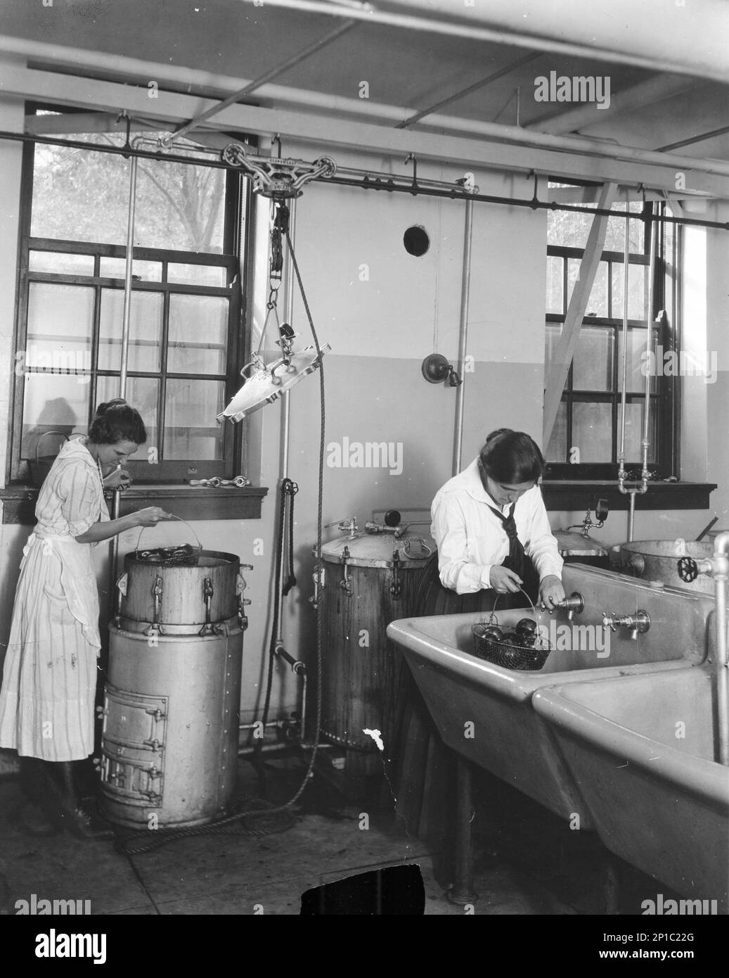 A team of people preparing fruit preserves with canning methods in a commercial kitchen, circa 1920, USA Stock Photo