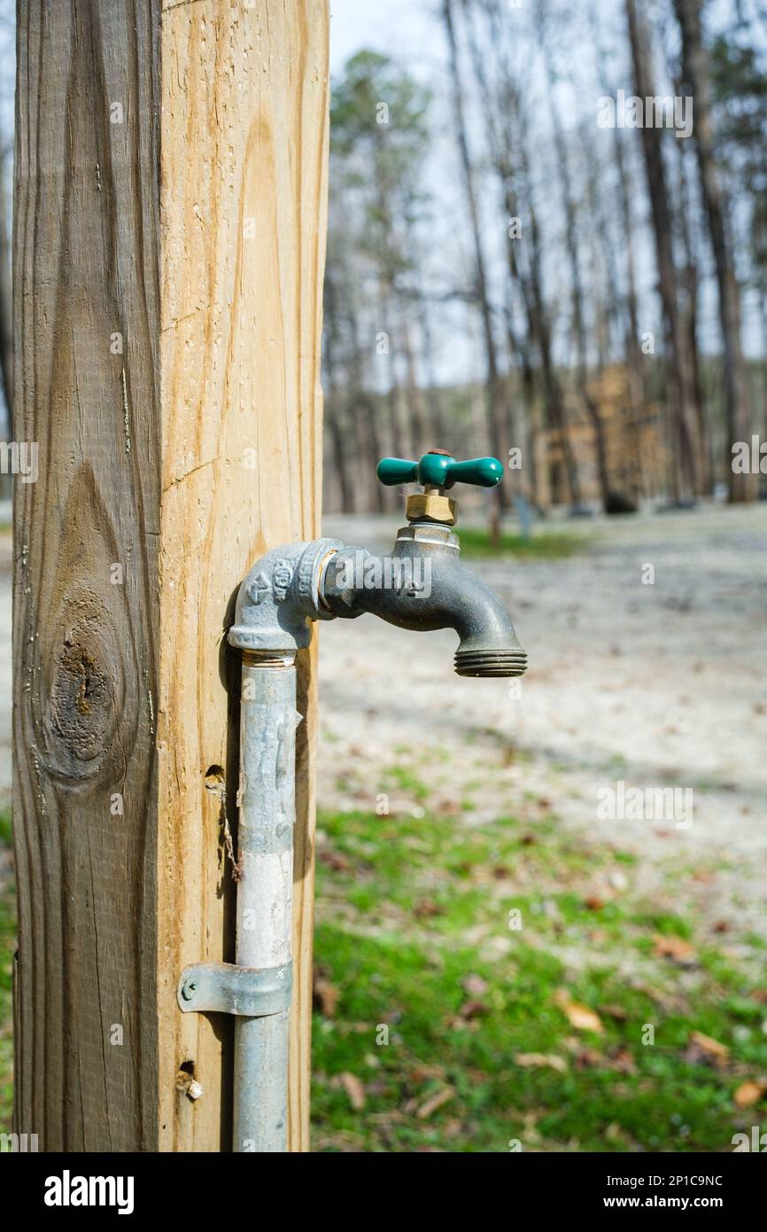 Clean water tap attached to a wooden post at a campground Stock Photo