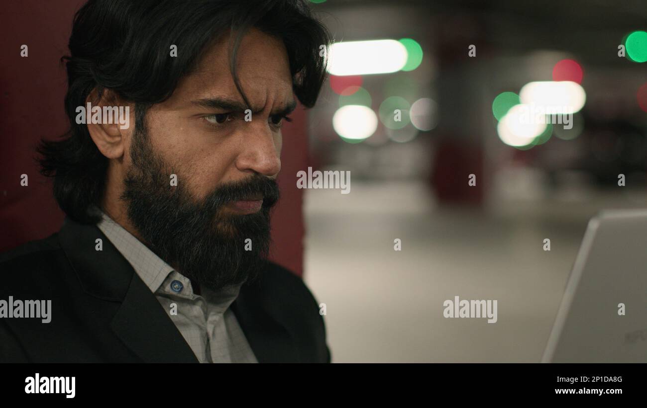 Close-up puzzled serious Indian man looking at laptop screen in ...
