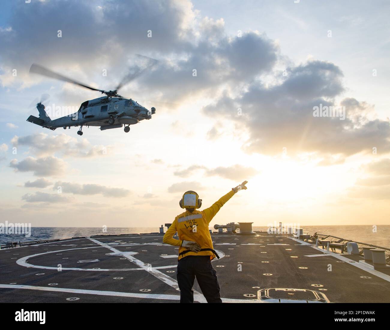 PHILIPPINE SEA (Jan. 21, 2023) Boatswains’s Mate 2nd Class Sarah Johnson, from Centura, Wisconsin, salutes an MH-60S during flight quarters aboard Arleigh Burke-class guided-missile destroyer USS Benfold (DDG 65) in the Philippine sea, Jan. 21. Benfold is assigned to Commander, Task Force (CTF) 71/Destroyer Squadron (DESRON) 15, the Navy’s largest forward-deployed DESRON and the U.S. 7th Fleet’s principal surface force. (U.S. Navy photo by Mass Communication Specialist 3rd Class RuKiyah Mack). Stock Photo