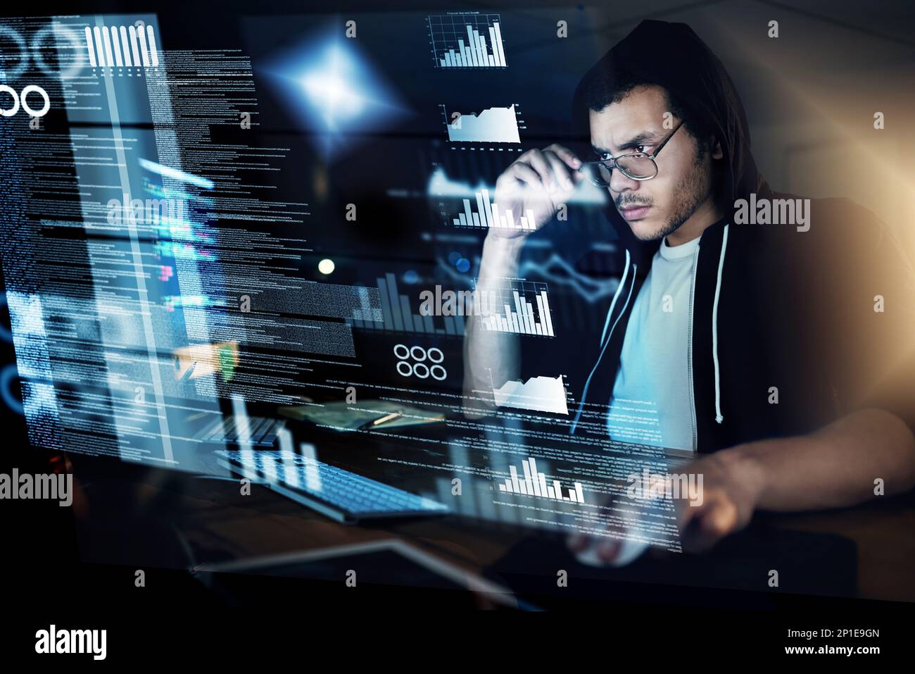 Encoding in progress. Shot of a young hacker cracking a computer code in the dark. Stock Photo