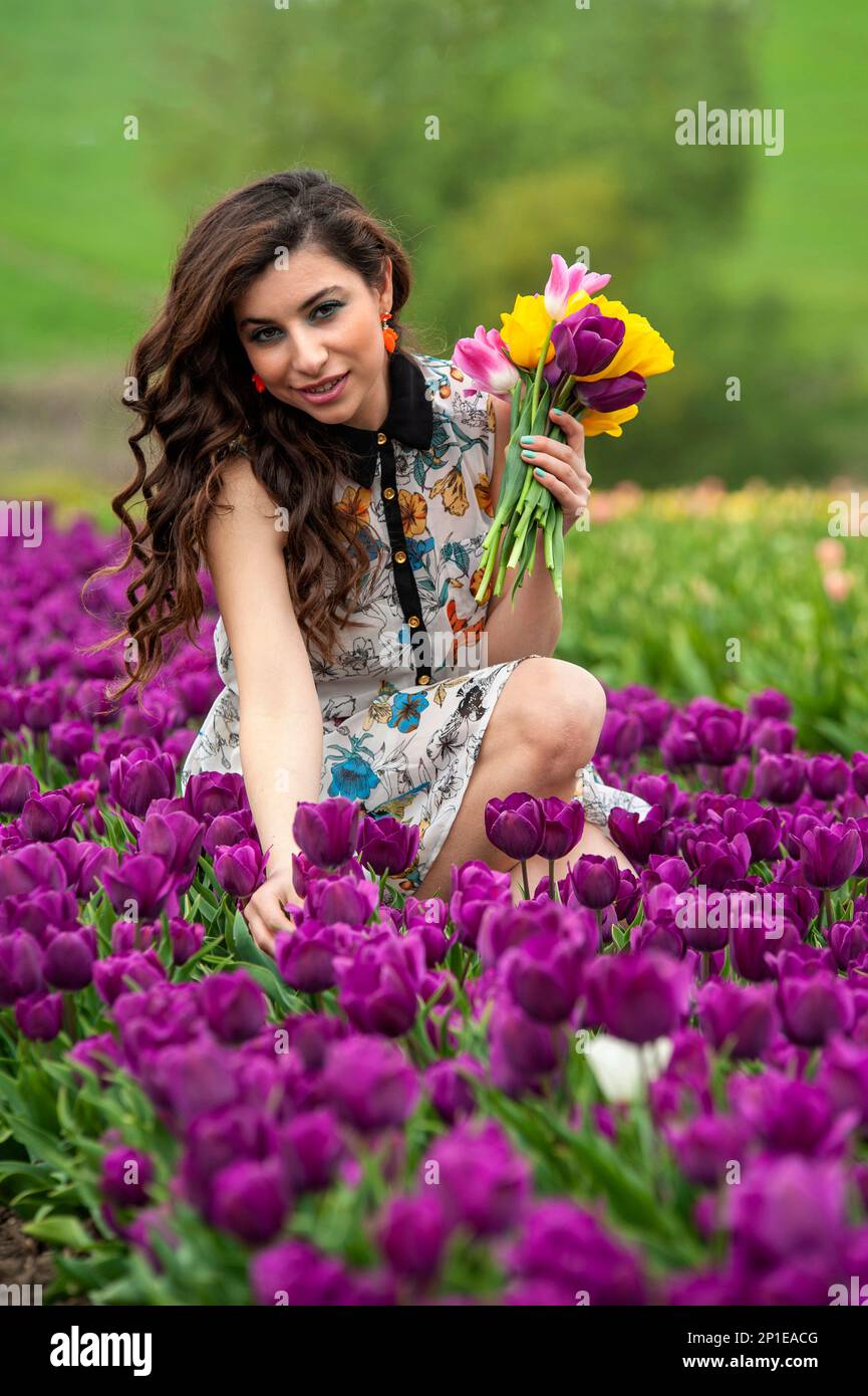 beautiful young woman with long hair in acolorfull dress with a bouquet ...