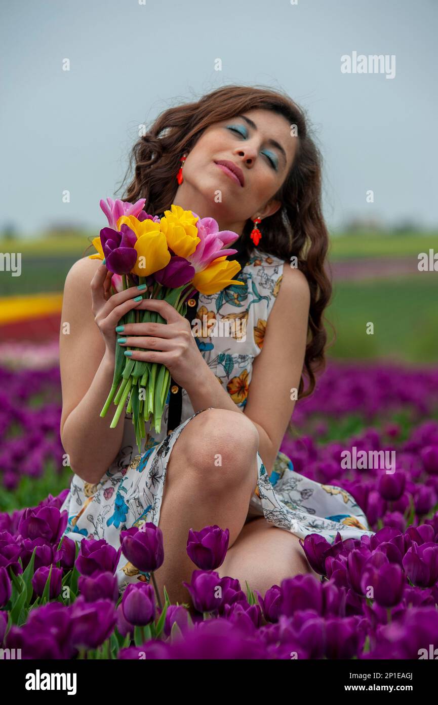 beautiful young woman with long hair in acolorfull dress with a bouquet ...