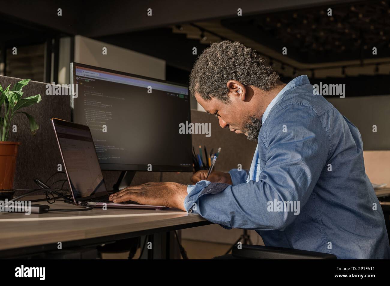 Black Man Writing Lines of Code On Desktop PC With Two Monitors and a ...