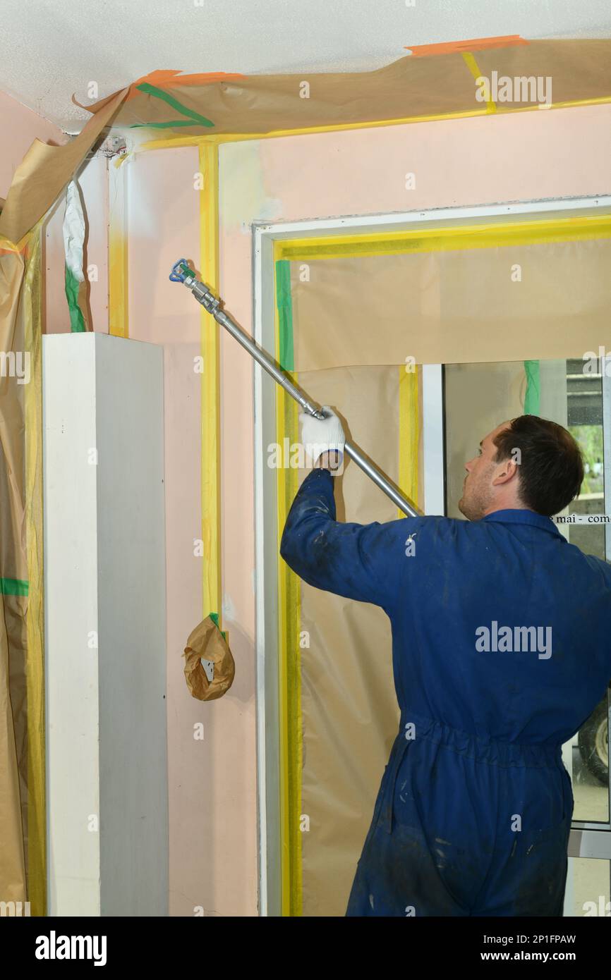 A painter applies an acrylic primer coat to the interior walls of a renovation building near Greymouth, South Island, New Zealand Stock Photo