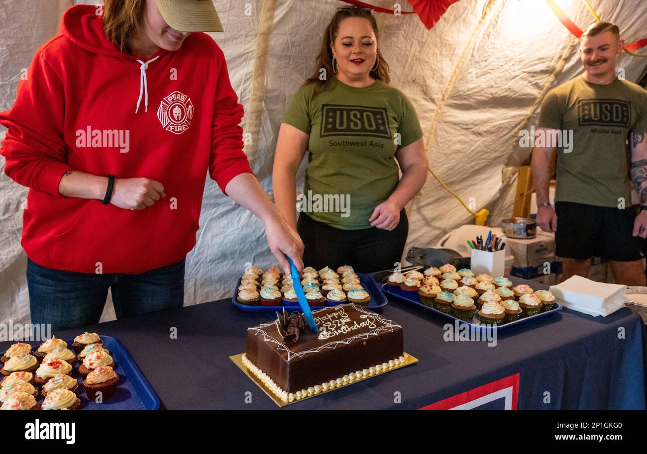 U.S. Air Force Chief Master Sgt. Jessica McWain, left, 378th Air Expeditionary Wing command chief, cuts a cake during USO Saudi Arabia's 82nd birthday party at Prince Sultan Air Base, Saudia Arabia, Feb. 4, 2023. The celebration included cake, balloons, raffle prizes and camaraderie. The USO has been serving U.S. military service members by keeping them connected to family, home and country since 1941. Stock Photo