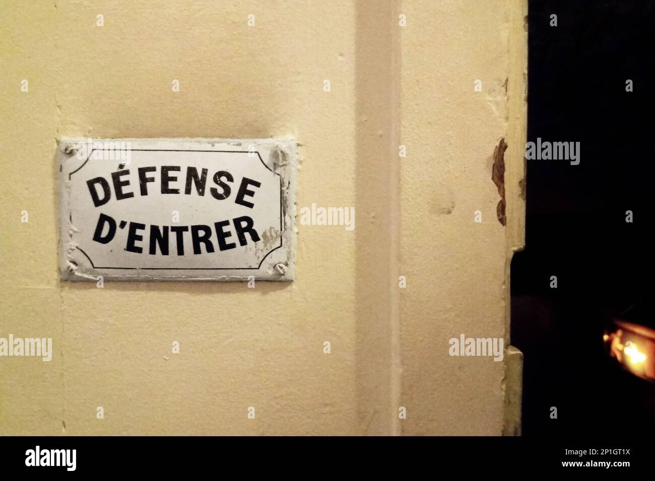 White plate screwed on a wall next to an open door saying in french