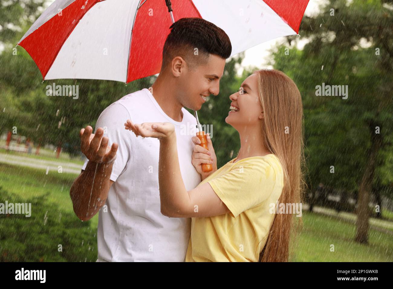 Lovely couple with umbrella walking under rain in park Stock Photo - Alamy