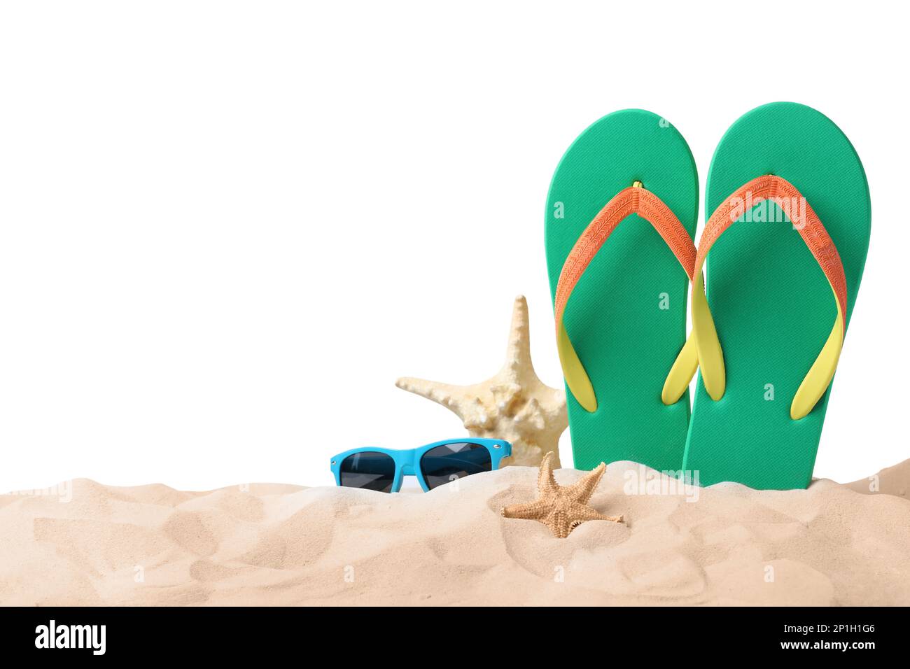 Green flip flops, starfishes and sunglasses on sand against white ...