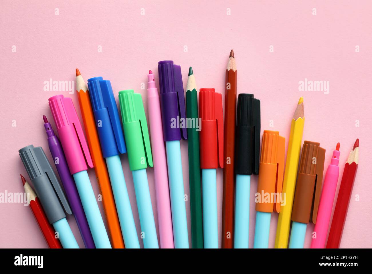 Different colorful pencils and felt tip pens on pink background, flat ...