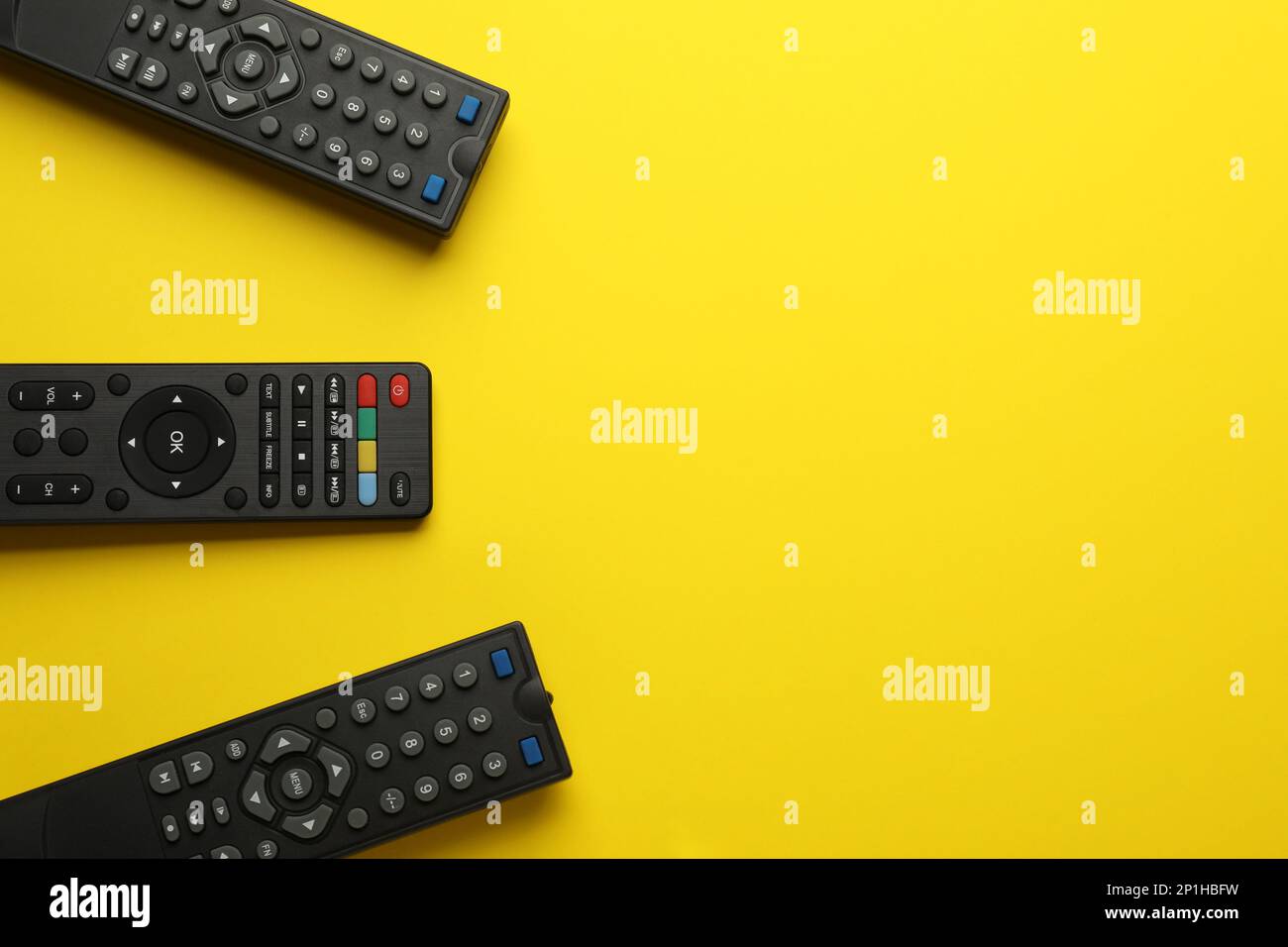 Remote controls on yellow background, flat lay. Space for text Stock Photo
