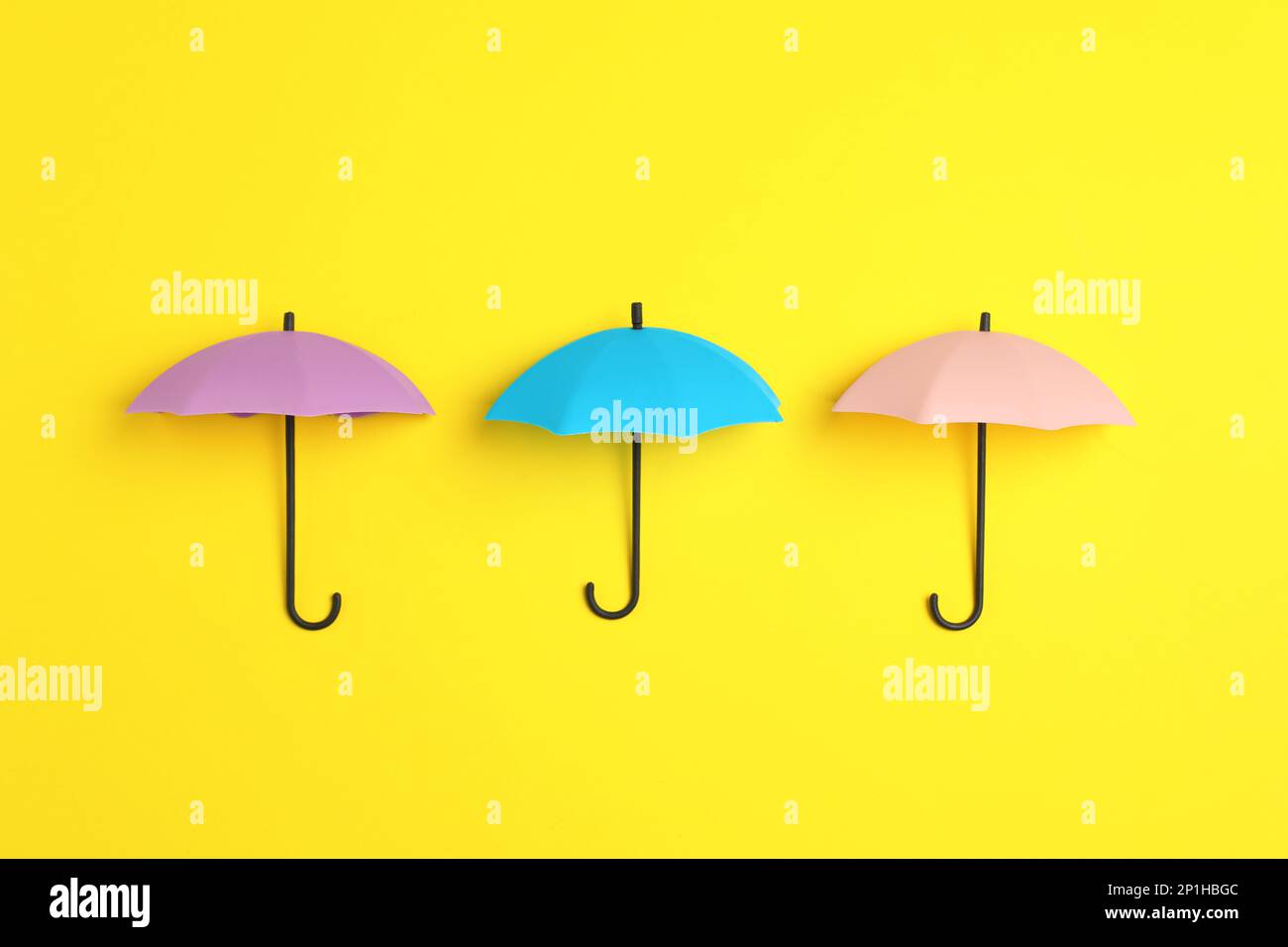 Bright toy umbrellas on yellow background, flat lay Stock Photo