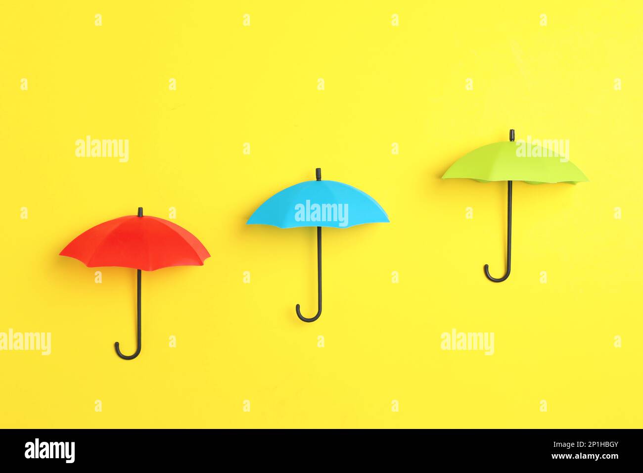 Bright toy umbrellas on yellow background, flat lay Stock Photo