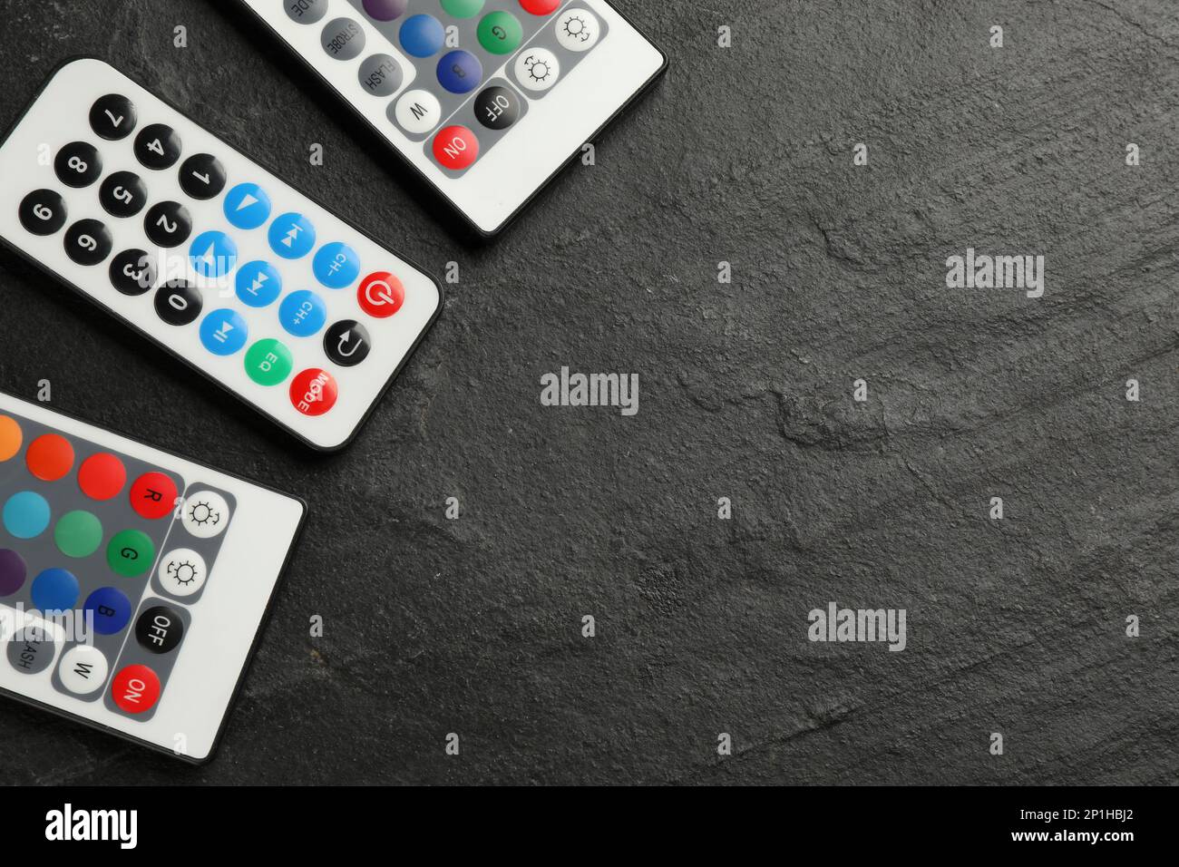Remote controls on black table, flat lay. Space for text Stock Photo