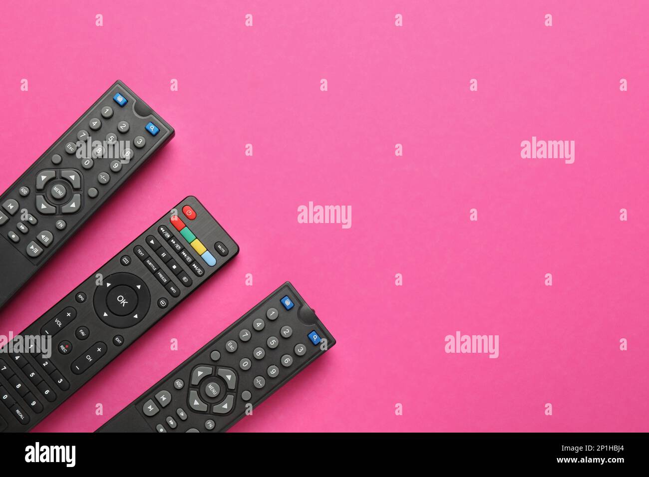 Remote controls on pink background, flat lay. Space for text Stock Photo