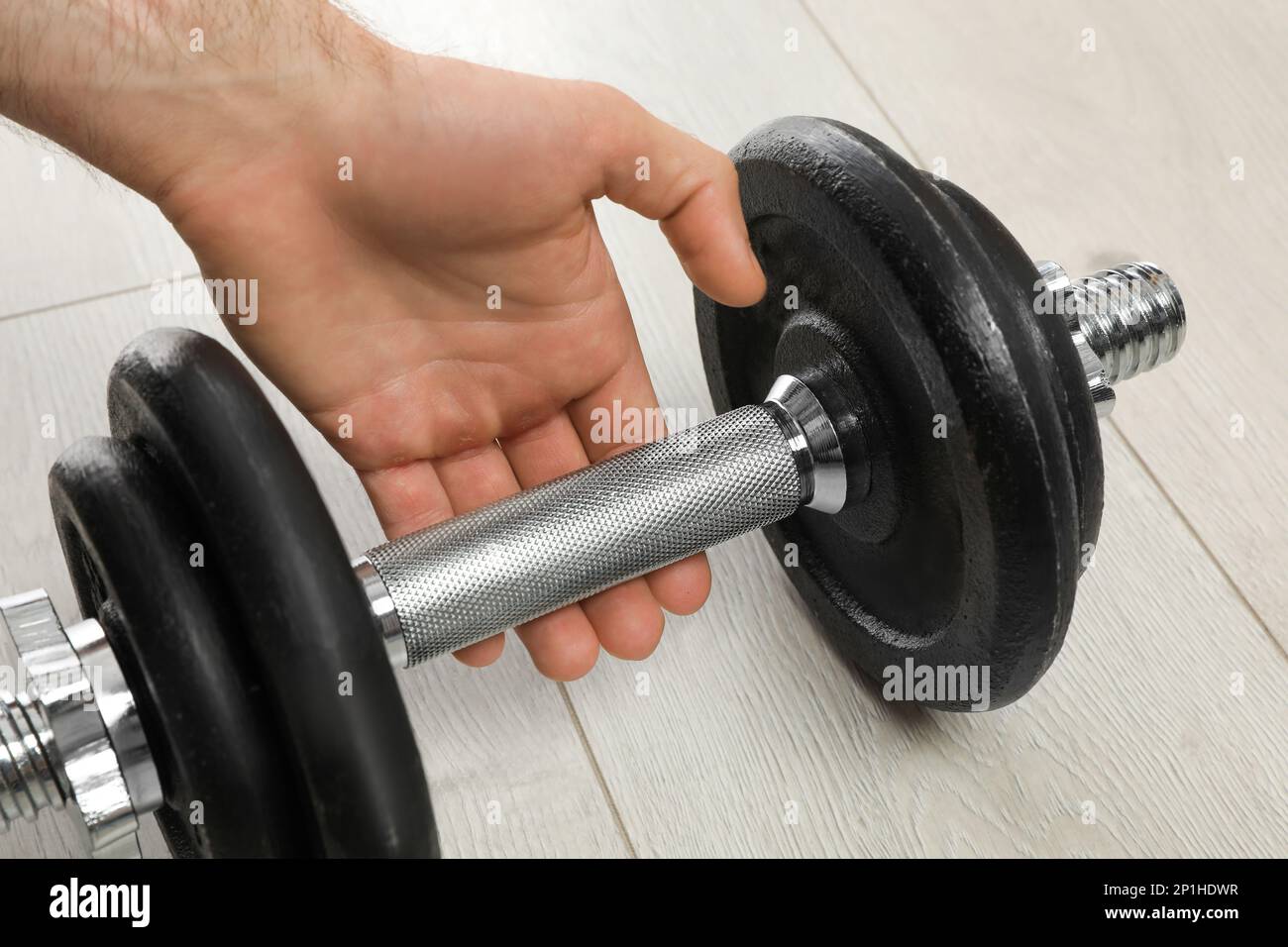 Sporty man taking dumbbell indoors, closeup. Suffering from calluses on