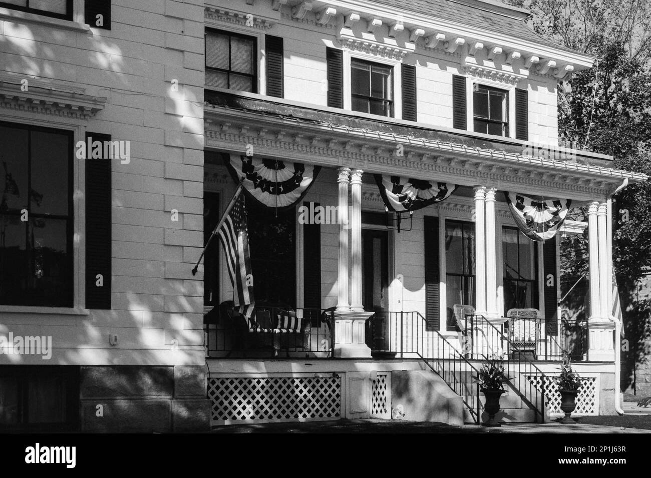 A historic home decorated with American flags and flourishes during the