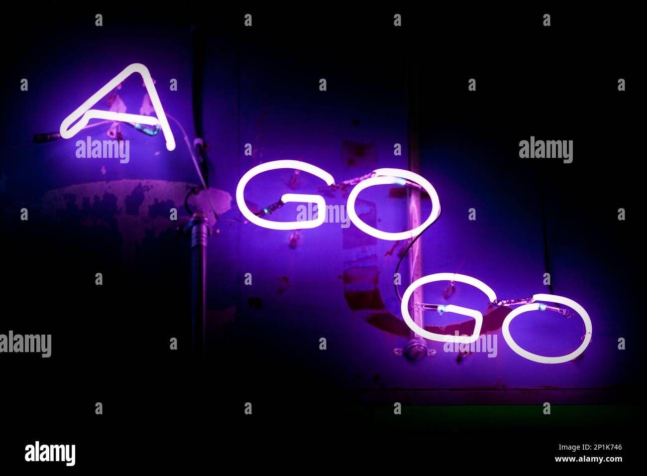 Close-up on a neon light shaped into the words "A go go" outside of a