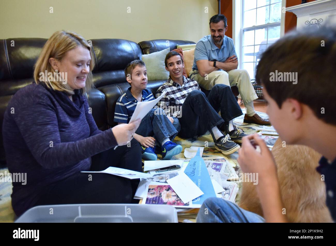 Julie Armas (left) reads one of hundreds of letters that the family received when the Hand of Hope photo went viral as (from left) Zachary (10), Samuel (16), Alex Armas and Ethan (12) listen at their home on Tuesday, February 16, 2016 in Villa Rica, Ga. Julie and Alex Armas have three sons and two of them, Samuel (16) and Zachary (10), have spina bifida. Julie had fetal surgery during her pregnancy with Samuel in hopes of repairing the lesion on his back. USA Today covered the controversial surgery and a photographer captured what has since become the famous "Hand of Hope", which captured Samu Stock Photo