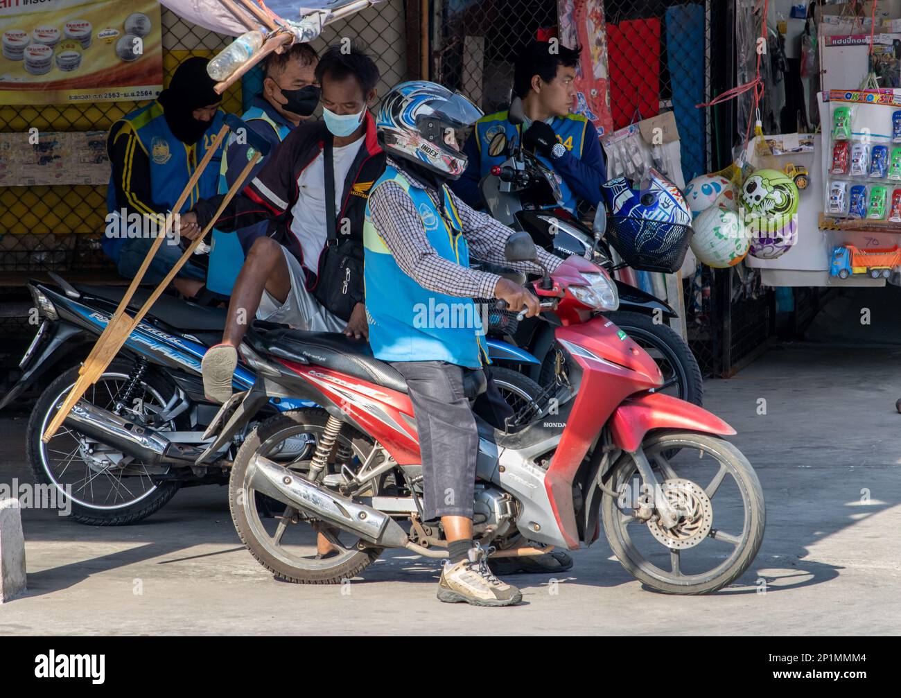SAMUT PRAKAN, THAILAND, FEB 13 2023, An elderly man with crutches gets on a moto taxi Stock Photo