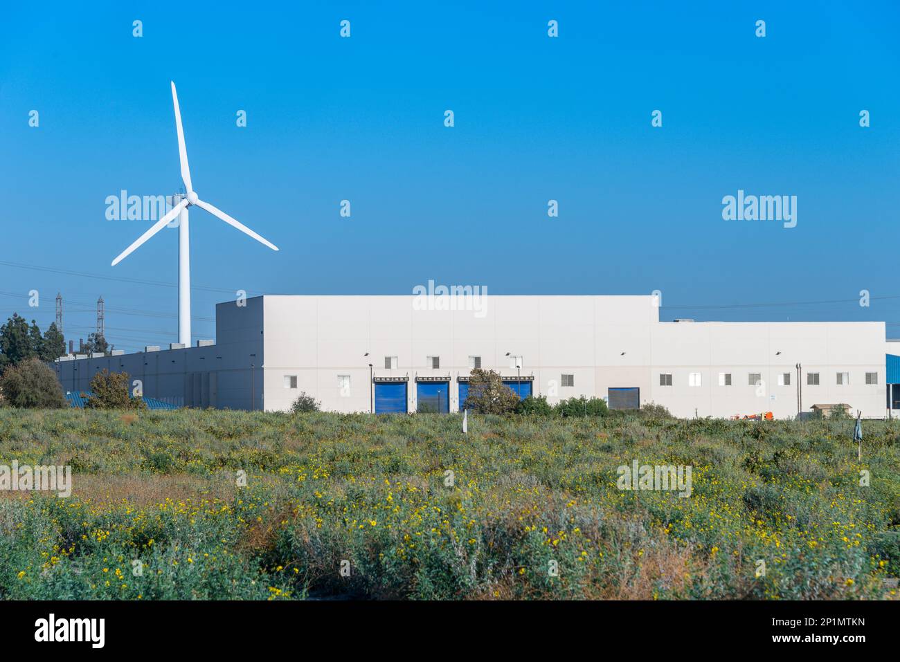 Wind Turbine behind and above large industrial building Stock Photo Alamy