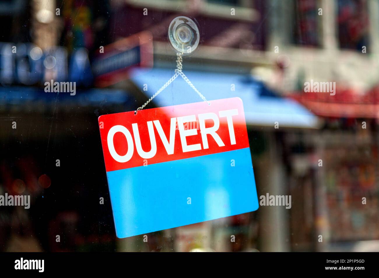 Red and blue sign in the window of a shop saying in French Ouvert, meaning  in English Open Stock Photo - Alamy