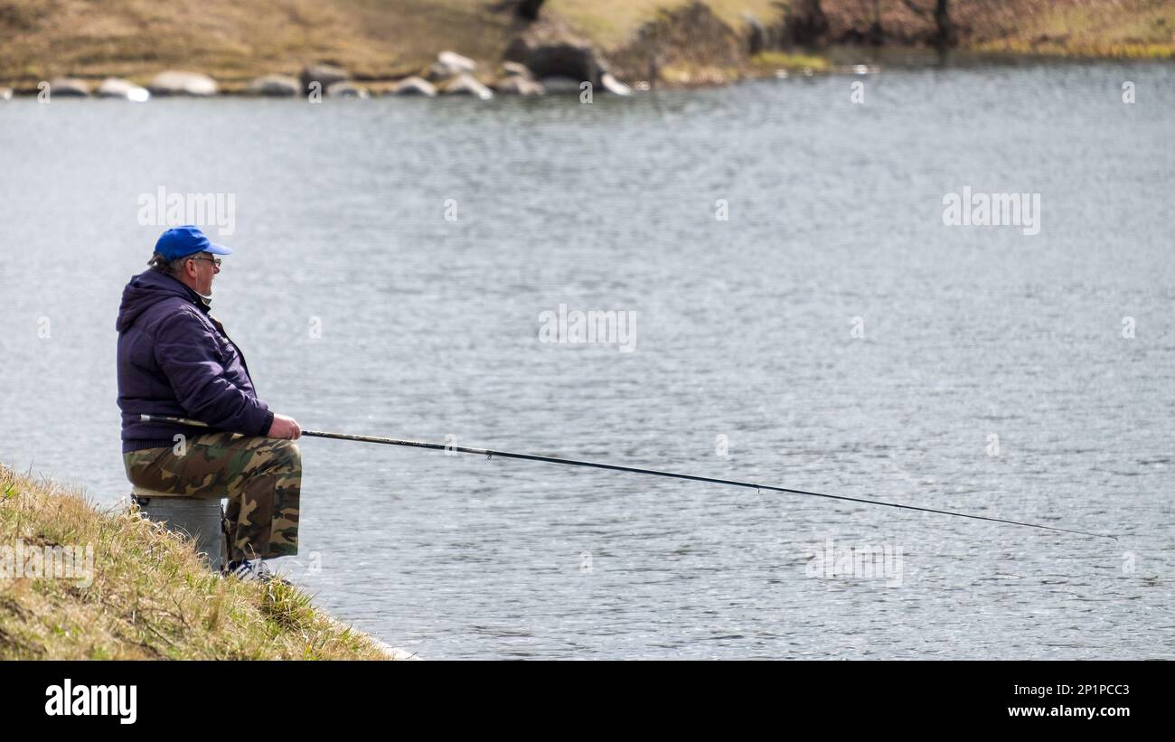 Minsk, Belarus - April 11, 2022:Fisherman with a fishing rod on the shore of the lake. Spring fishing Stock Photo