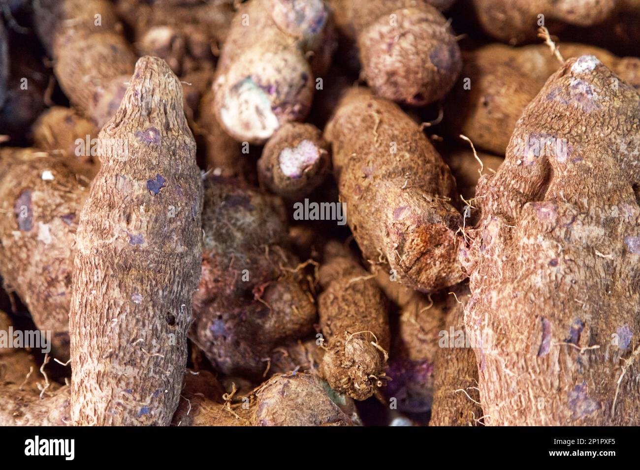 Full frame close-up on a stack of purple yams on a market stall. Stock Photo