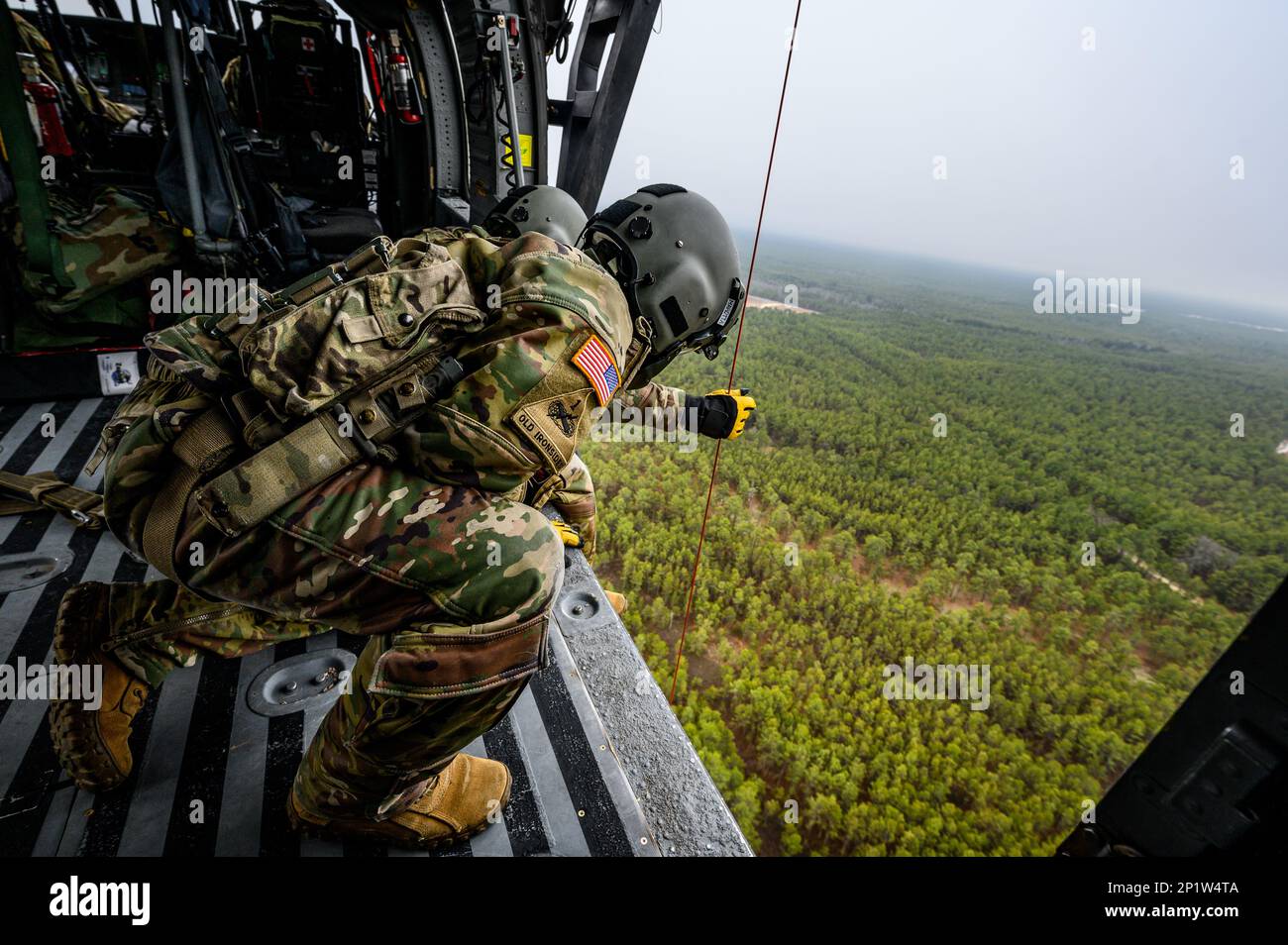 U.S. Army Staff Sgt. Anthony Marotta, a UH-60L Black Hawk helicopter crew chief, with the New Jersey National Guard's 1-150th Assault Helicopter Battalion, watches as the hoist lowers at Joint Base McGuire-Dix-Lakehurst, New Jersey, Jan. 5, 2023. The crew chiefs work with the Detachment 2, Charlie Company, 1-171st General Support Aviation Battalion in the hoist training. Stock Photo
