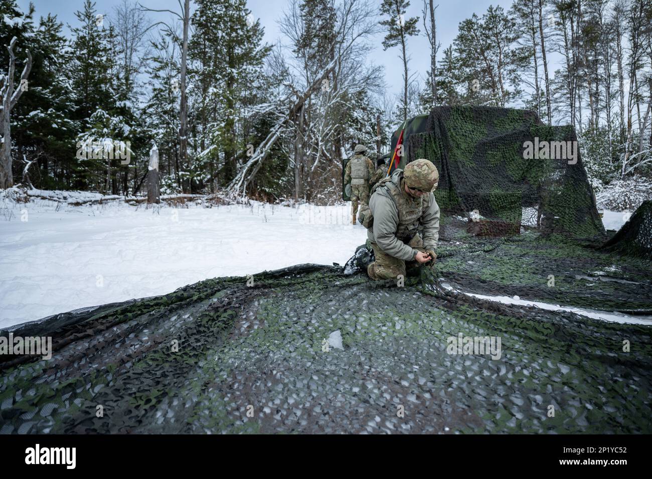 Army Spc. Francis Sprecher, 1-120th Field Artillery Regiment, sews together a camouflage canopy while setting up an M119 howitzer during Northern Strike 23-1, Jan. 25, 2023, at Camp Grayling, Mich. Units that participate in Northern Strike’s winter iteration build readiness by conducting joint, cold-weather training designed to meet objectives of the Department of Defense’s Arctic Strategy. Stock Photo