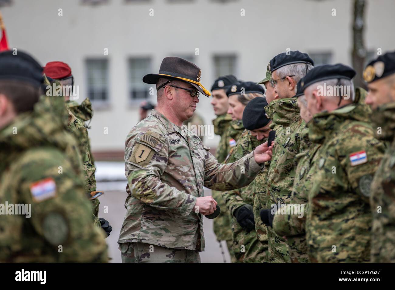 U.S. Army Sgt. 1st Class Michael Adams, acting first sergeant of Forward Support Company, 3rd Battalion, 8th Cavalry Regiment, 3rd Armored Brigade Combat Team, 1st Cavalry Division, operationally controlled by the 1st Infantry Division (1 ID), removes a Croatian soldier’s unit patch during the NATO patch ceremony as a part of the Hand Over, Take Over ceremony in Bemowo Piskie, Poland, Jan. 24, 2023. The Croatian army is among other units assigned to the 1 ID, proudly working alongside NATO allies and regional security partners to provide combat-credible forces to V Corps, America's forward dep Stock Photo