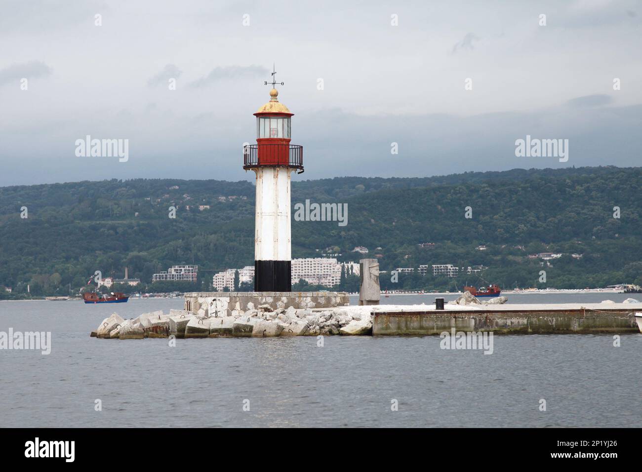 White lighthouse tower with red top stands at the entrance breakwater ...