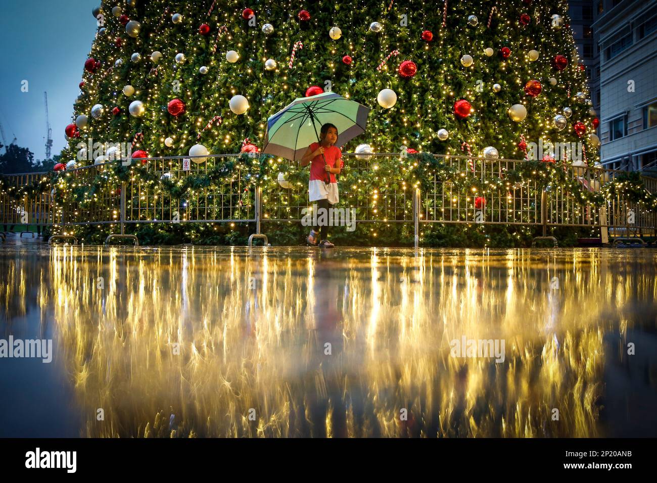 A young Malaysian girl walks in front of a Christmas tree at a mall in