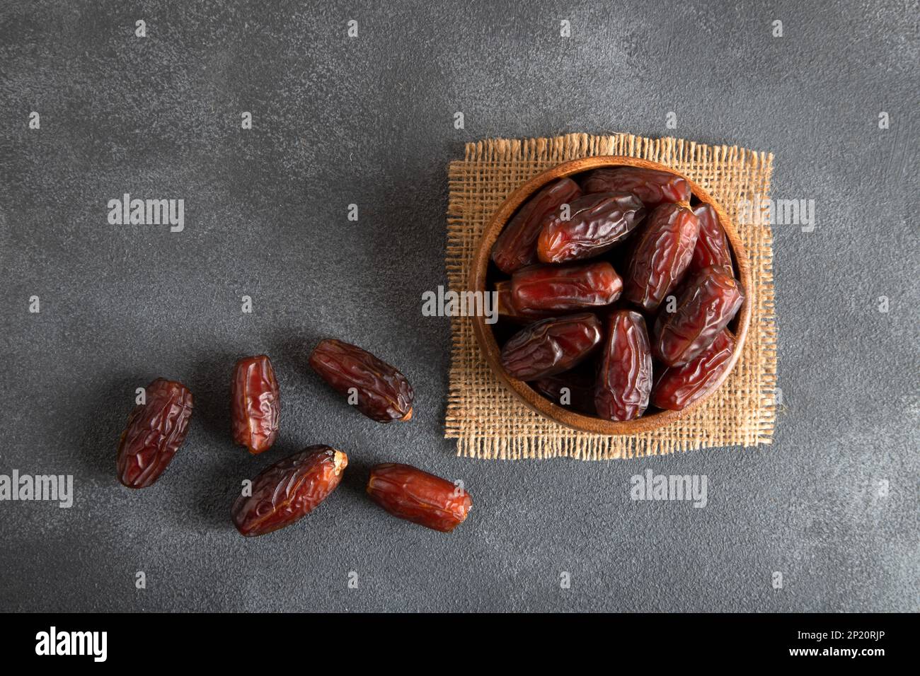 Date fruits in wooden bowl on black background,top view Stock Photo - Alamy