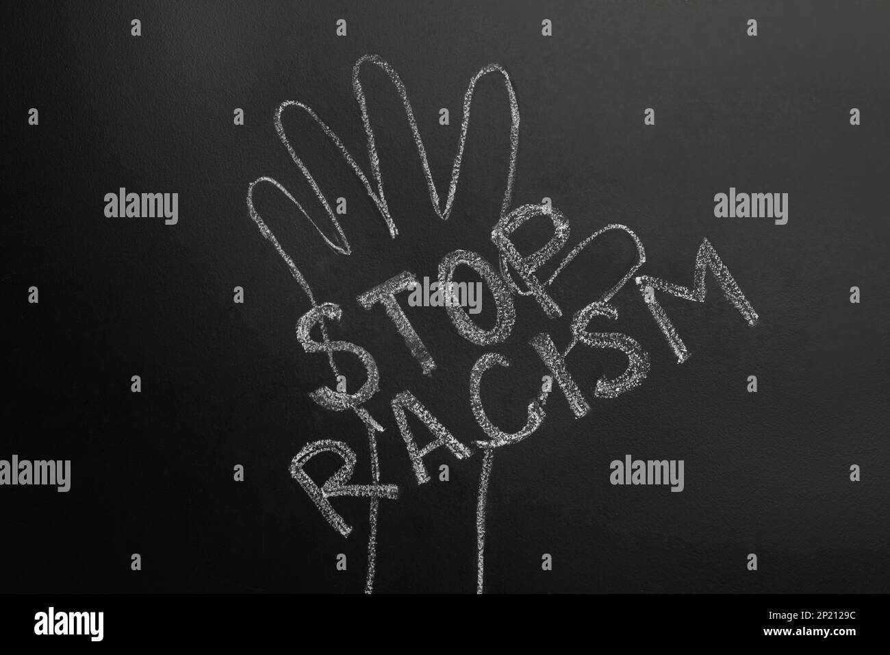 Chalked inscription Stop Racism and raised hand on blackboard Stock Photo