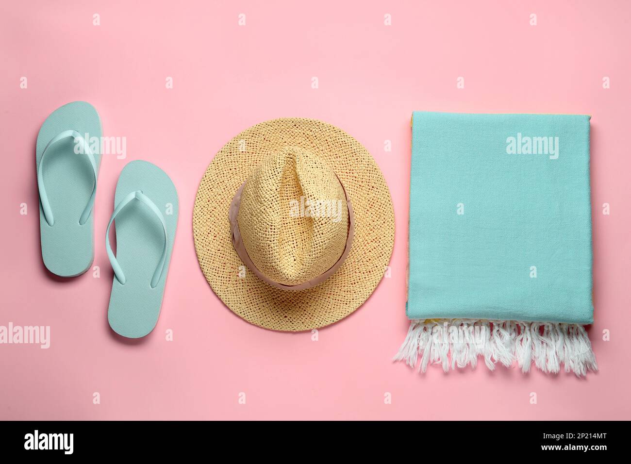 Beach towel, flip flops and straw hat on pink background, flat lay ...