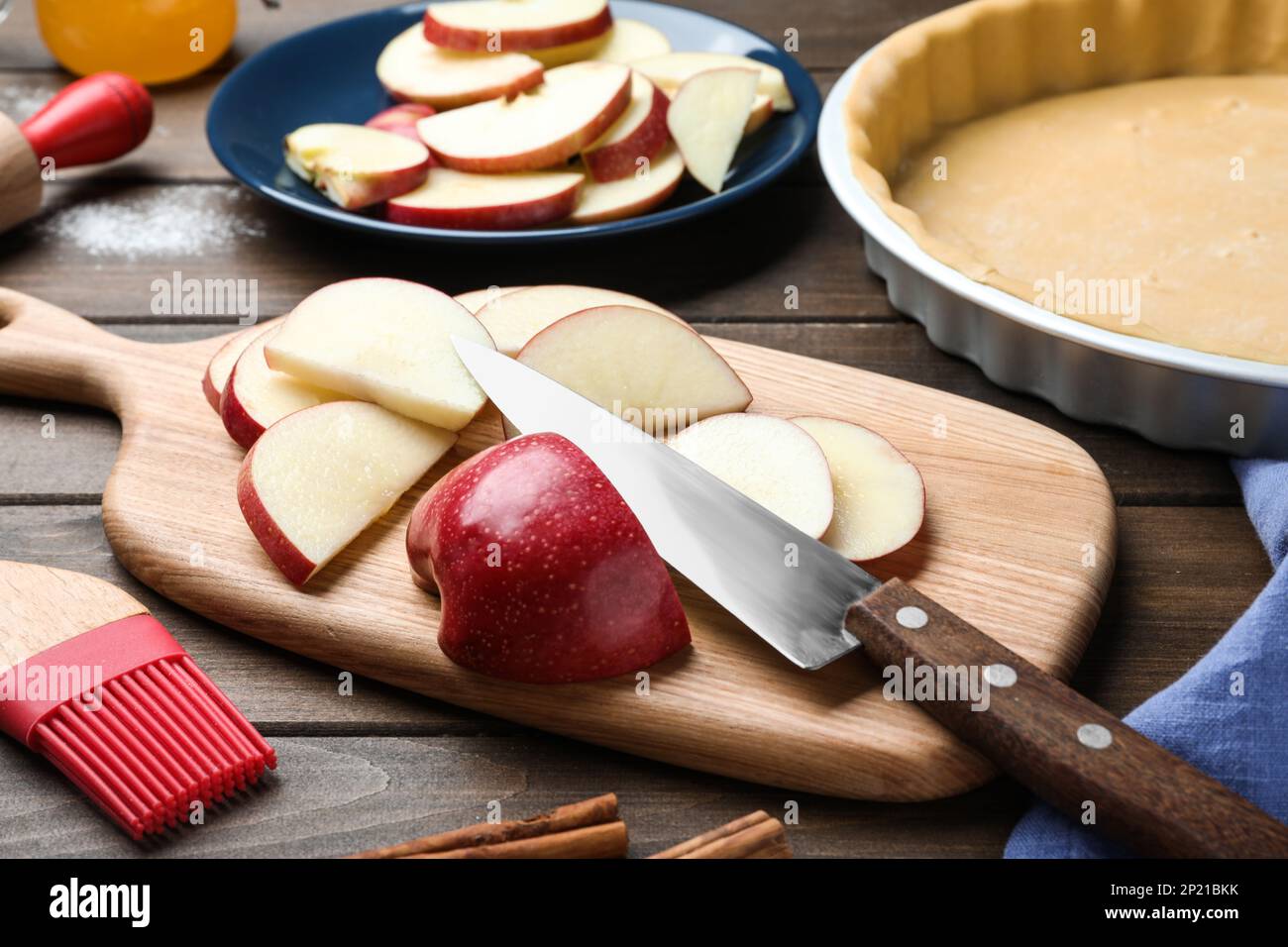 Cut fresh apple with knife and board on wooden table. Baking pie Stock Photo