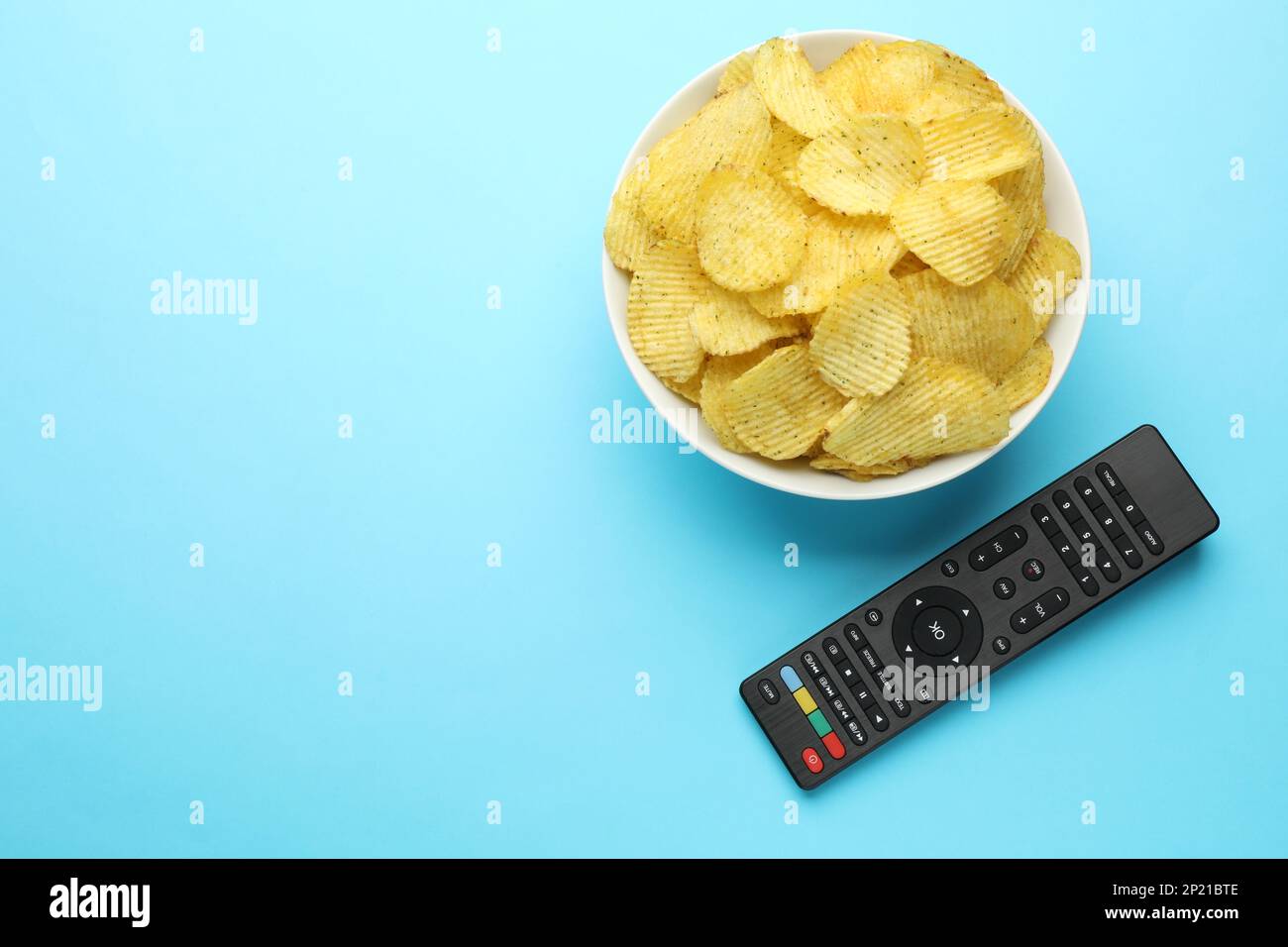 Conroll Chips Remote control and bowl of potato chips on light blue background, flat ...
