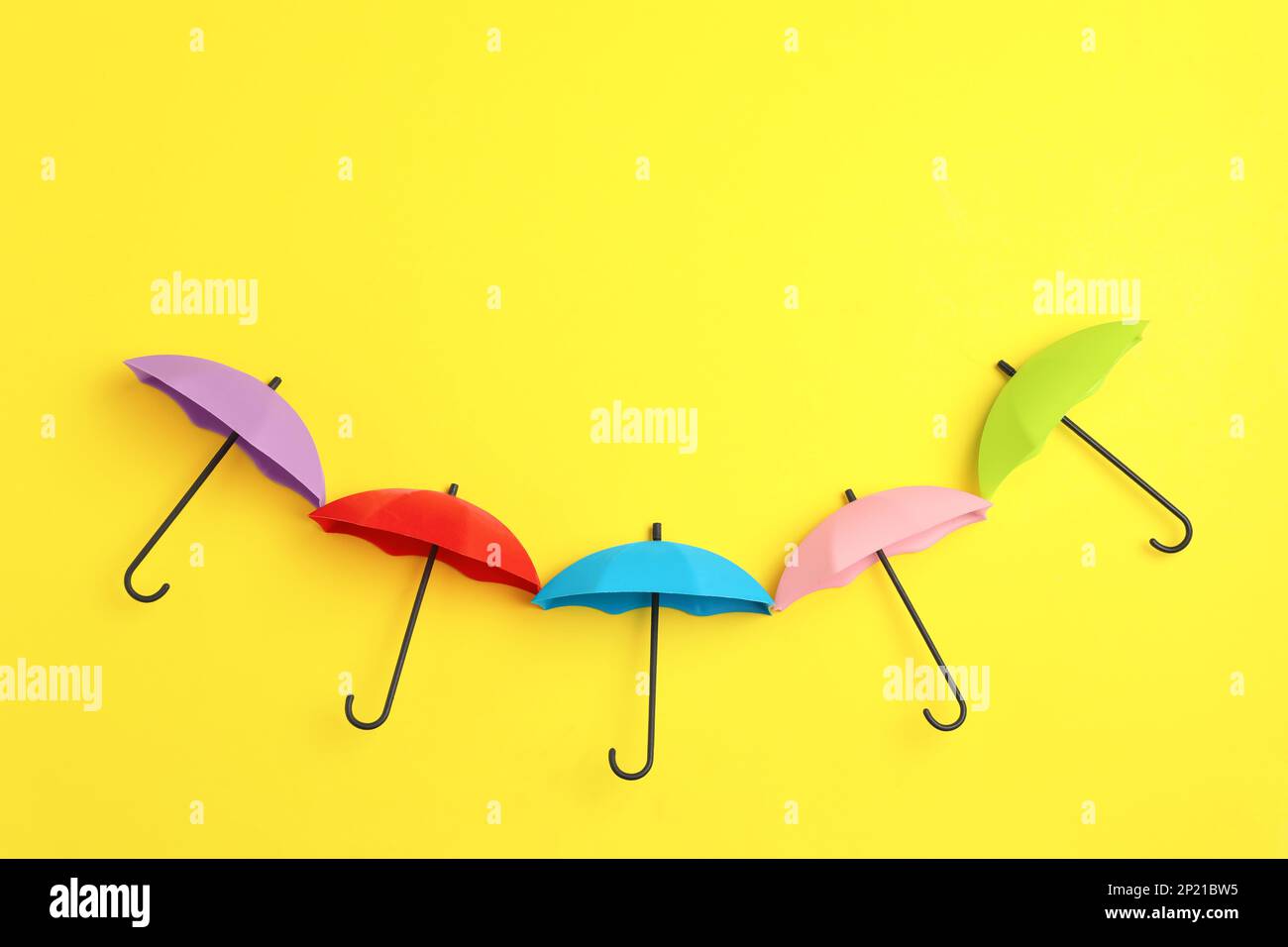 Bright toy umbrellas on yellow background, flat lay Stock Photo