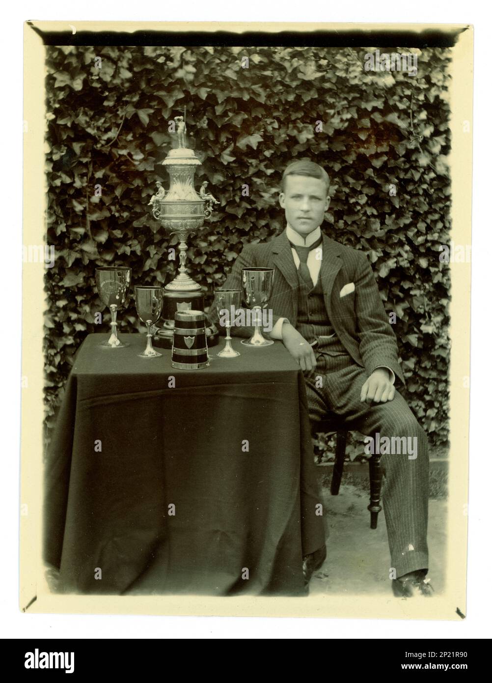 Original Victorian photograph of gent, on a table there is displayed a large Worcester challenge vase, / regatta trophy for rowing, and other cups, Possibly member of a coxed four crew. Worcester area, U.K.  circa 1897-1899. Stock Photo