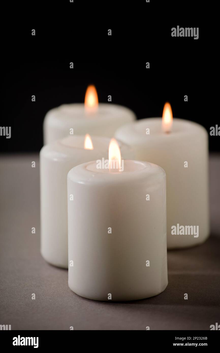 set of burning white candles on the shelf with black background Stock ...