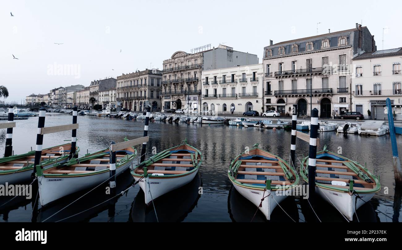 Desaturated photo, of the facades of the Maréchal De Lattre de Tassigny quay on the royal canal and typical boats, in Sète, Occitanie, France Stock Photo